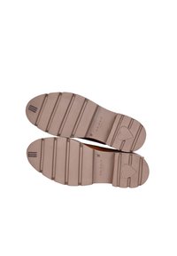 Sole di scarpe in gomma di colore marrone chiaro con modelli scanalati, caratterizzate da una forma a cuore e marchi in rilievo. Texture liscia con dettagli antiscivolo.