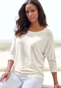 Light beige top with 3/4 sleeves, featuring a subtle wavy pattern. The fabric appears soft with a relaxed fit.