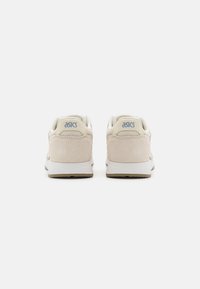 Beez suede tossud valgete kummitaldadega, millel on võrgust pealmine osa ja helesinine ASICS logo kandadel. Ümar varvas ja pehmendatud krae.