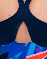 Bañador azul marino con diseño de corte en la espalda, que presenta patrones geométricos coloridos en azul, rosa y rojo en la sección inferior.