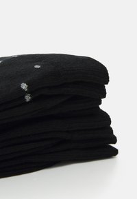 Zwarte sokken gestapeld met een zachte, ribbelige textuur. Bevat verspreide zilveren stippen voor detail. Lichtgewicht en veelzijdig voor casual draag.