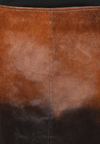 Saia de couro castanho em degrade, com uma textura suave, apresentando um gradiente que vai do castanho claro na parte superior ao castanho escuro na parte inferior.