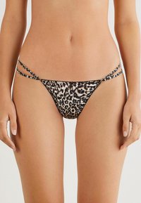 Bas de bikini à imprimé léopard avec de fines bretelles croisées. Fabriqué en tissu doux, il présente une coupe taille basse et un design à couverture minimale.
