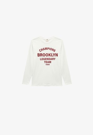 Langärmliges weißes T-Shirt aus Baumwolle mit rotem Text: "CHAMPIONS BROOKLYN LEGENDARY TEAM 1986" in einem fetten, gewölbten Design.