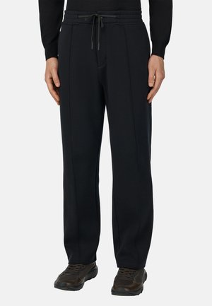 Pantalones de chándal negros de tela suave con cintura ajustable, que cuentan con dos bolsillos frontales y costuras limpias para un detalle adicional.