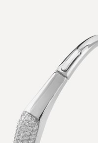 Srebrna oprawka okularów o gładkim, zaokrąglonym kształcie, z teksturowanym, zdobionym kamieniami świątem dla dodatkowego detalu i wizualnego zainteresowania.