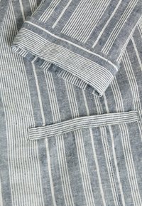 Blue and white striped fabric with a folded sleeve and a horizontal welt pocket detail on a garment.
