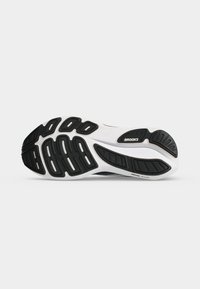 Sole of a Brooks running shoe with black rubber tread patterns on a white base, shown against a plain light grey background.