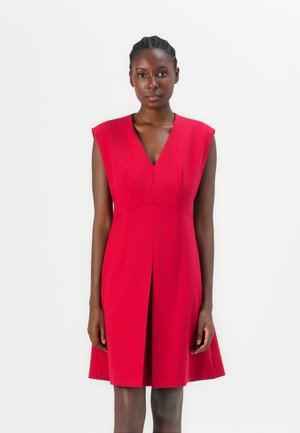 Robe rouge sans manches avec un décolleté en V, jupe évasée et plis à l'avant, fabriquée à partir d'un tissu lisse et structuré.