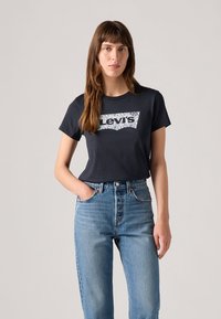 T-shirt en coton bleu marine avec un logo graphique Levi's en blanc et bleu. Associé à un jean en denim taille haute bleu clair.