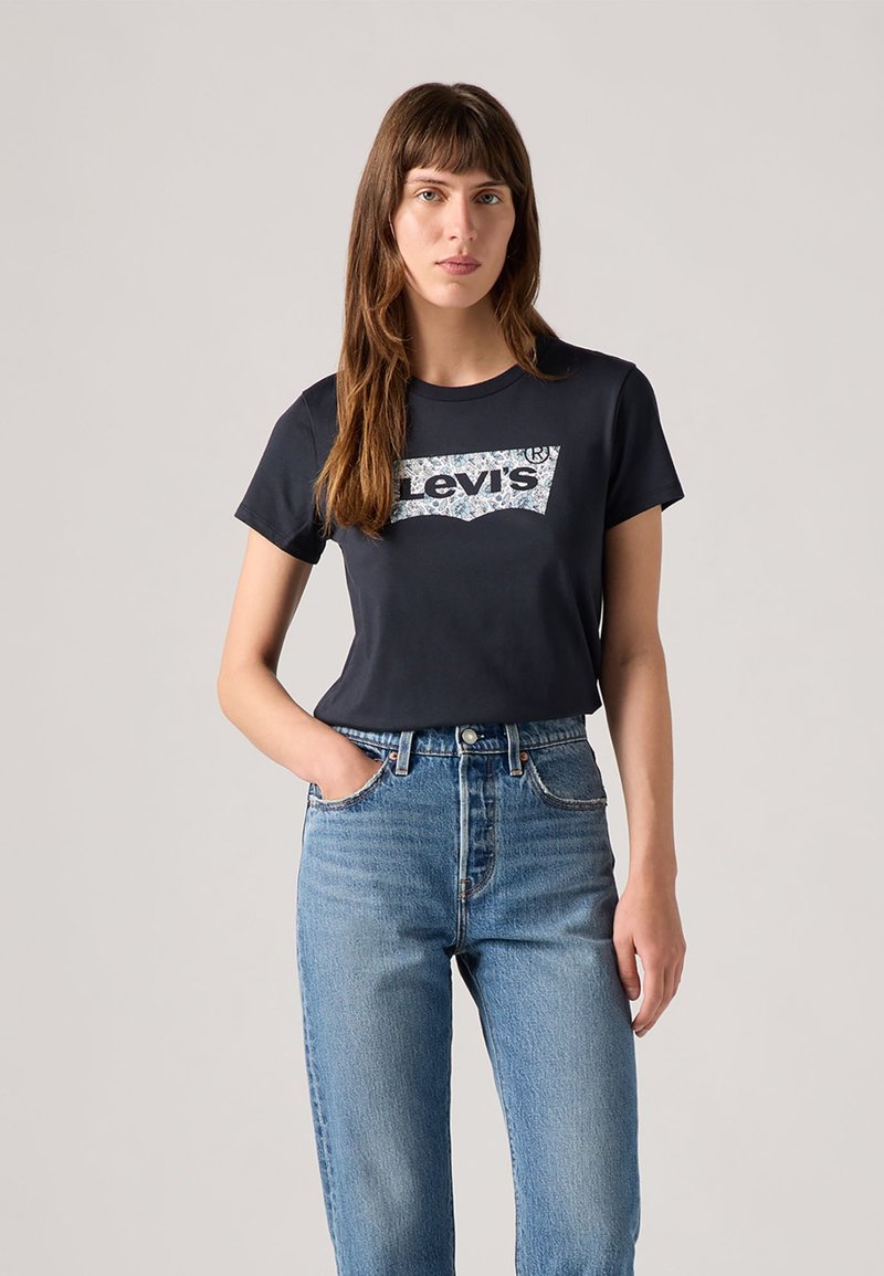 Navy-Baumwoll-T-Shirt mit einem grafischen Levi's-Logo in Weiß und Blau. Kombiniert mit hellblauen, hoch taillierten Jeans.