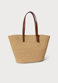 Pleteni ručno tkani torba od slame s ručkama od smeđe kože. Ima suženi oblik i zlatni ukras s logotipom. Prirodna boja s teksturiranim završetkom.