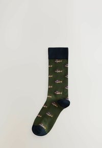 Grüne Socken mit navyfarbigem Bund, die ein wiederholtes Fischmuster in Pink, Gelb und Blau aufweisen. Hergestellt aus weichem Textilmaterial.
