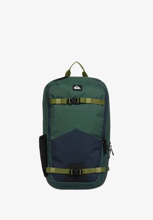 Sac à dos vert et bleu marine avec deux sangles horizontales réglables et boucles à déclenchement rapide noires, poignée supérieure et poche latérale en filet.