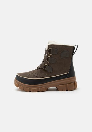 Bruine veter-winterlaars met dikke zool, zwarte rubberen bies onderaan en witte fleece voering binnenin.