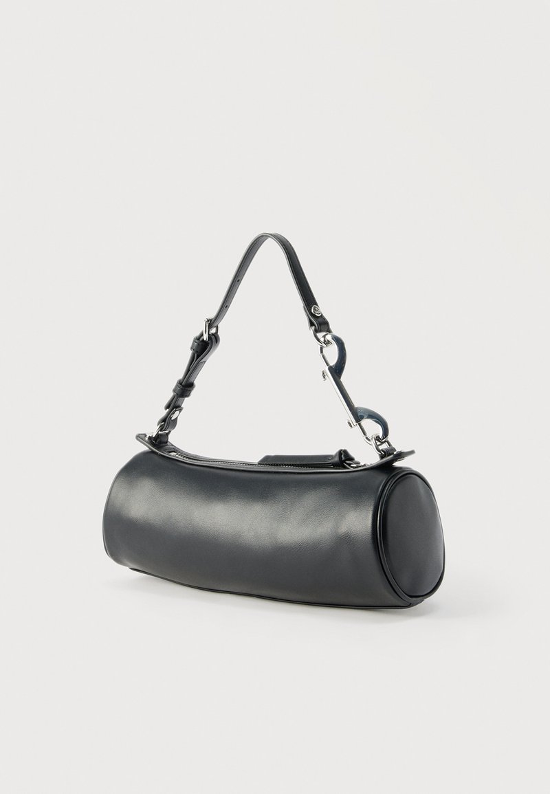 Schwarze zylindrische Ledertasche mit verstellbarem Riemen und silberner Hardware vor schlichtem hellem Hintergrund.