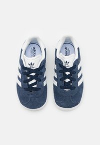 Navy blue suede sneakers with white three stripes, round toe, lace-up design, and cushioned white interior lining.