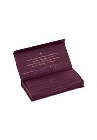 Lila rechteckige Box mit einem goldenen Innenraum, die eine Seiden-Augenmaske enthält. Der Text enthält Entspannungsthemen und elegante Designelemente.