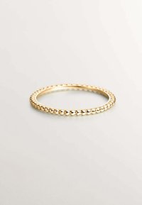 Anillo de color dorado con textura de cuentas, con un acabado suave y pulido. Diseño circular simple, sin adornos adicionales.