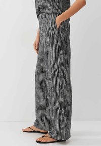Black and white patterned wide-leg pants with a loose fit, featuring side pockets and a textured grid design. Made of lightweight fabric.