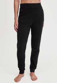 Zwarte joggingbroek gemaakt van een zachte stof, met een geribbeld elastiek in de taille en bij de boorden, en met zijzakken voor extra gemak.