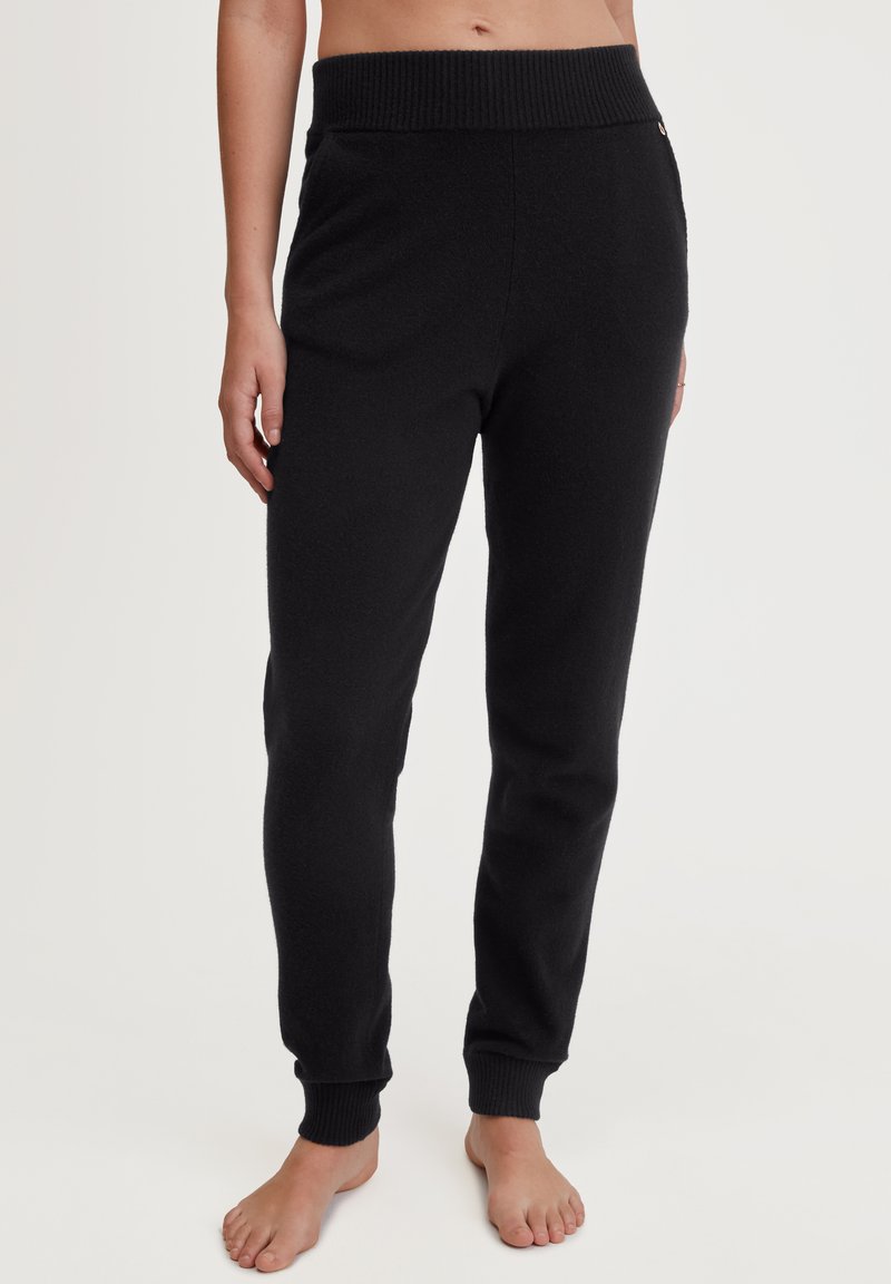 Zwarte joggingbroek gemaakt van een zachte stof, met een geribbeld elastiek in de taille en bij de boorden, en met zijzakken voor extra gemak.