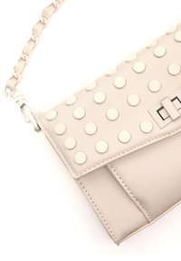 Borsa beige realizzata in pelle liscia, dotata di una patta decorata con grandi borchie color crema e una tracolla a catena per il trasporto.