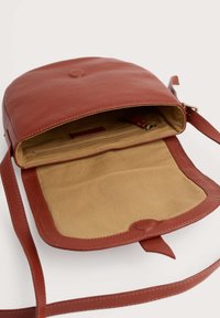 Borsa a tracolla rossa in pelle con una texture liscia, chiusura a scatto magnetico e un interno beige vuoto con tasca con zip.