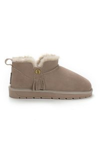 Beige mokkasiner med faux fur-foring, rund tå, kvastdetalj og en liten pull-tab bak. Flat gummisåle.