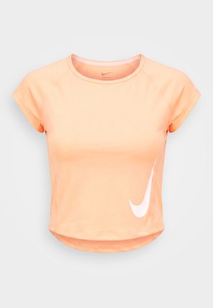 T-shirt de sport femme à manches courtes, orange clair, avec un col rond et un swoosh Nike blanc en bas à droite.