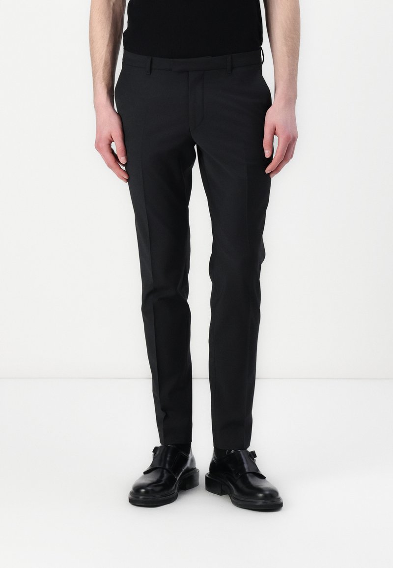 Schwarze maßgeschneiderte Hose aus glattem Stoff, mit schlanker Passform und geraden Beinen, kombiniert mit schwarzen Lederschuhen.