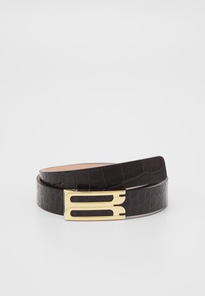 Tummanruskea krokotiilityylillä kuvioitu nahkavyö, jossa on kullanvärinen kaksinkertainen solki. Vyö on sileä, kiiltäväpintainen ja kapenee päistä.