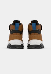 Un paio di scarpe da escursionismo marroni con suole nere, intersuola bianca, tiranti blu sul tallone e etichette impermeabili in Gore-Tex viste da dietro.