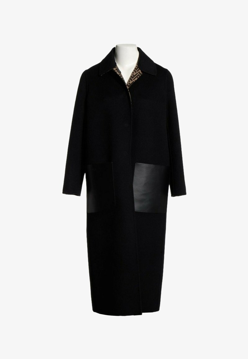 Long manteau noir avec un large col, deux grandes poches avant en cuir et une doublure intérieure à motifs visible au niveau de l'encolure.