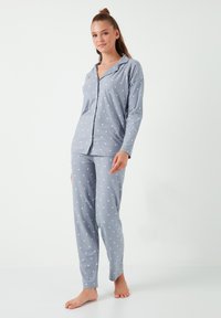 Ensemble de pyjama à pois gris, fabriqué en tissu doux, comprenant un haut à manches longues, une chemise à boutonnière et un pantalon assorti à coupe décontractée.