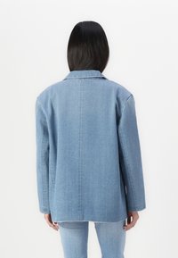 Denim jakna v svetlo modri barvi z ohlapnim krojem, dolgimi rokavi in ovratnikom. Ima vidno šivanje in raven rez na robu.