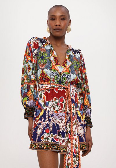 Colorful patterned blouse featuring a v-neck, puff sleeves, and a cinched waist. Made from lightweight fabric with assorted floral and geometric designs.