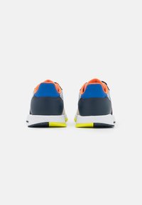 Scarpe sportive con tacco in pelle blu navy, dettagli blu e arancioni, suola intermedia bianca, suola esterna gialla e tomaia in rete traspirante.