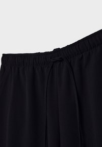 Zwarte sportbroek met een elastische tailleband, verstelbaar trekkoord, gladde textuur en subtiele naaddetails.