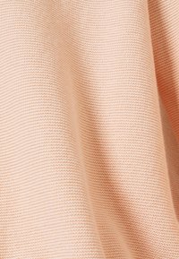 Persiko-färgad stickad tyg med ett fint, texturerat mönster som har horisontella ränder. Mjukt och lätt med en draperande framtoning.