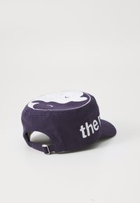 Lilla bomullslue med et hvitt grafisk design på toppen og ordet "the" brodert i hvitt på siden. Justerbar stropp bak.