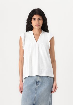 White, short-sleeved top with a V-neckline, featuring eyelet fabric and subtle ruffles at the shoulder. Paired with a denim skirt.