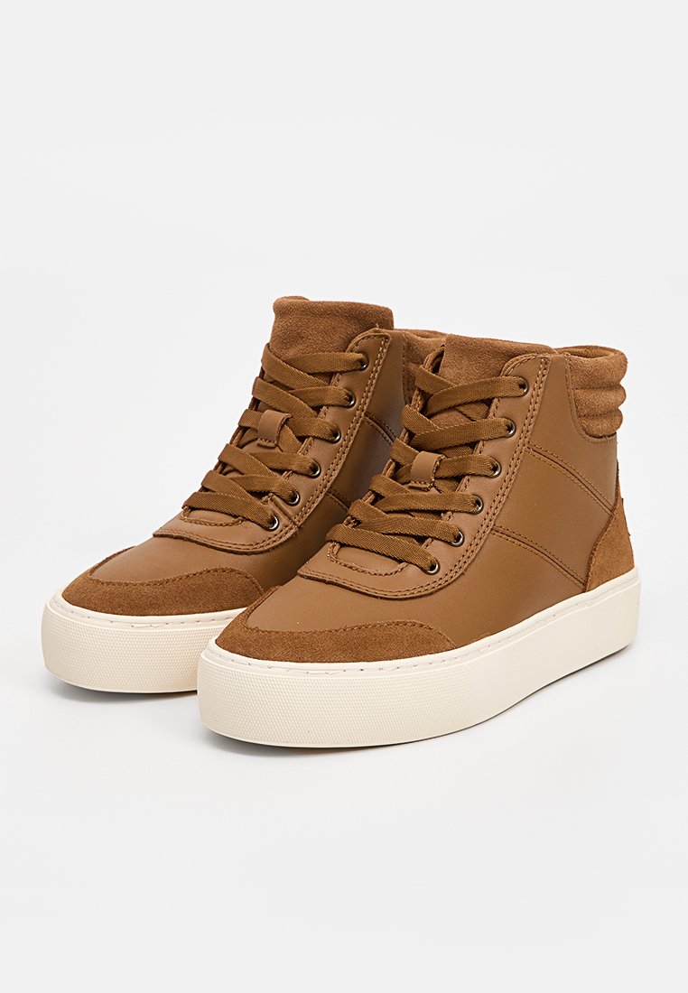 Bruine hoge sneakers gemaakt van leer en suède, met een textuurovervlak, vetersluiting en een contrasterende witte rubberen zool.