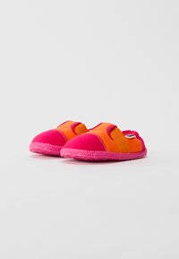 Bērnu slip-on apavi ar rozā zolem un pirkstu aizsargiem, oranžiem auduma augšdaļām un elastīgām siksnām augšpusē uz baltas fona.