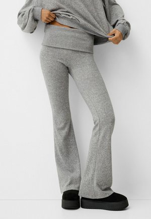 Gray, soft knit flared leggings with a high waistband, paired with black platform shoes. The fabric has a subtle texture and flexibility.