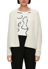 Ivoren gebreide cardigan met open voorkant, geribbeld textuur, lange mouwen en een iets cropped lengte, gecombineerd met een witte, gemusterde blouse.