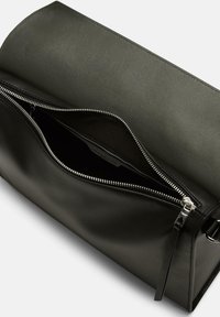 Czarna skórzana torba z zapięciem na zamek, gładką fakturą, kanciastym kształtem oraz srebrnymi detalami, z widokiem na wnętrze komory.