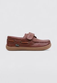 Zapato de cuero marrón tipo slip-on con una correa de Velcro, costuras decorativas, acentos de cordones laterales y una suela de goma flexible.