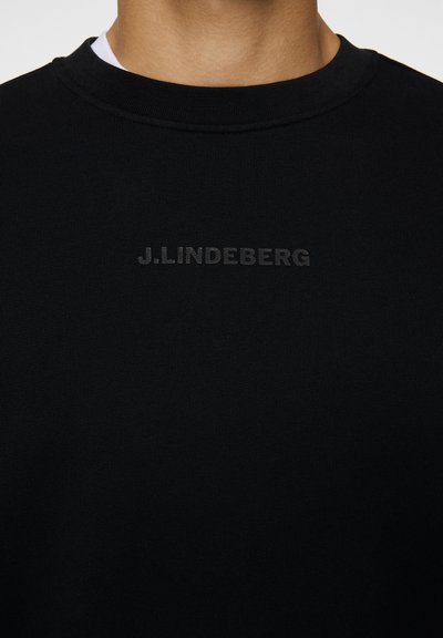 Sort sweatshirt med rund halsudskæring, lavet af et glat stof. Har et diskret, præget logo "J.LINDEBERG" på brystet.