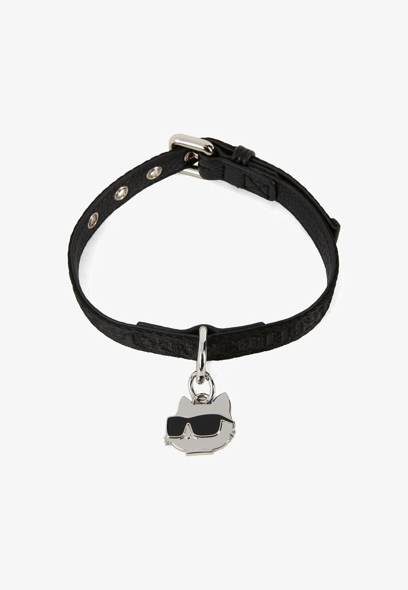 Mustan nahka rannekoru, jossa on teksturoitu pinta ja hopeinen kissa-riipus, jolla on päällään mustat aurinkolasit. Säädettävä metallinapeilla.